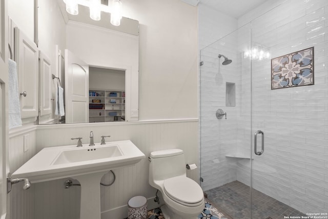 bathroom featuring a shower with door, ornamental molding, and toilet