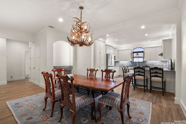 dining space with crown molding, dark hardwood / wood-style floors, and a notable chandelier