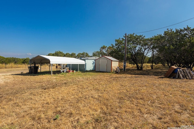 view of yard featuring a carport, a rural view, and a shed