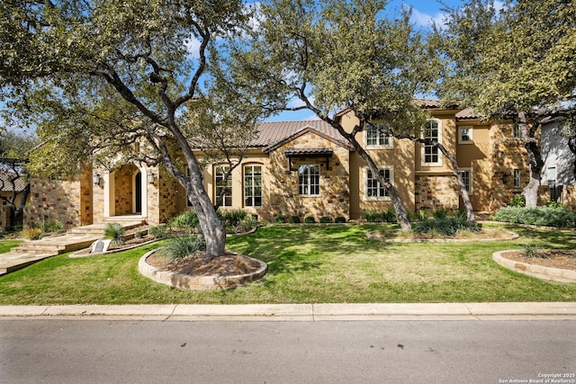 view of front of property with stone siding, a front yard, stucco siding, and a tiled roof