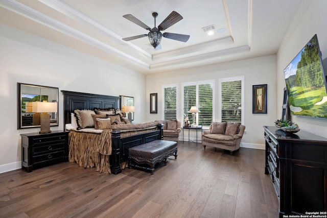 bedroom with baseboards, visible vents, ornamental molding, dark wood-style flooring, and a tray ceiling