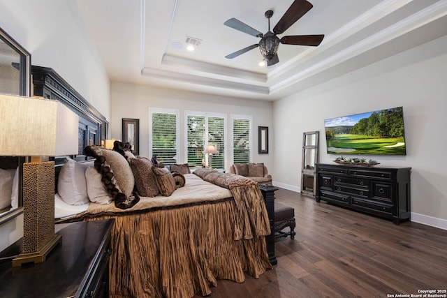 bedroom with a tray ceiling, dark wood-style flooring, visible vents, and baseboards