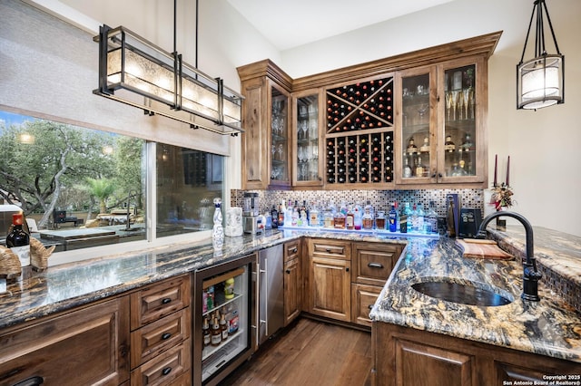 bar featuring wine cooler, a sink, hanging light fixtures, decorative backsplash, and wet bar