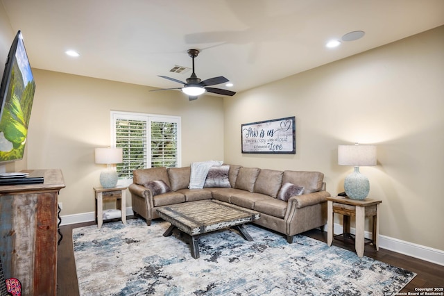 living area featuring dark wood-type flooring, visible vents, baseboards, and a ceiling fan