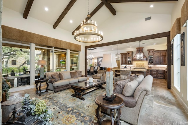 living room featuring high vaulted ceiling, stone tile flooring, a notable chandelier, and beam ceiling