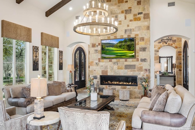 living area with visible vents, arched walkways, beam ceiling, and a stone fireplace