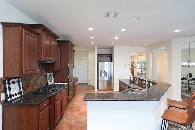 kitchen featuring backsplash, sink, dark stone countertops, appliances with stainless steel finishes, and a chandelier