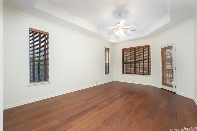 unfurnished room featuring dark hardwood / wood-style flooring, a tray ceiling, ceiling fan, and ornamental molding