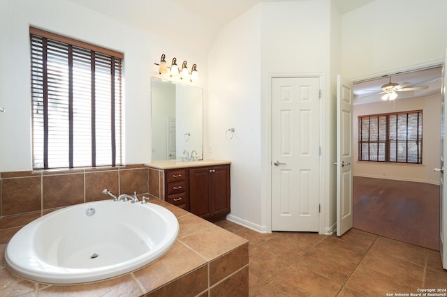 bathroom featuring tile patterned flooring, vanity, tiled bath, and ceiling fan