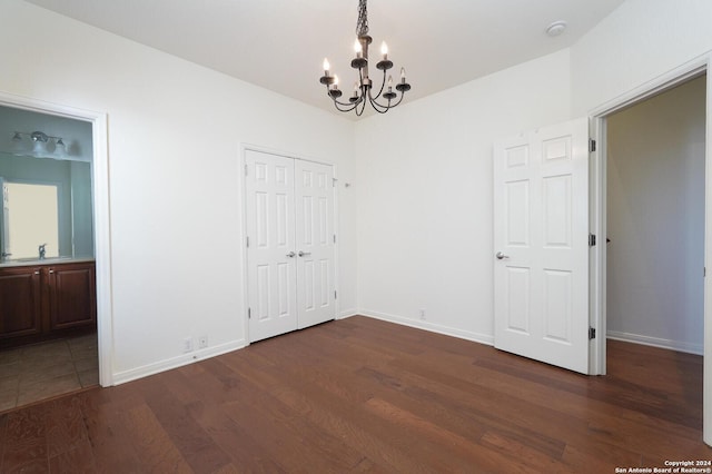 interior space with ensuite bath, sink, a chandelier, dark hardwood / wood-style floors, and a closet