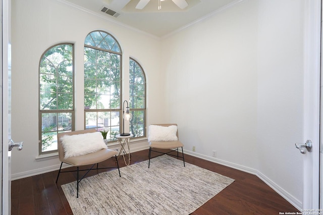 living area featuring dark wood-type flooring, ceiling fan, and crown molding