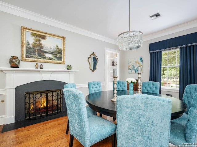 dining space with hardwood / wood-style floors, crown molding, and a notable chandelier