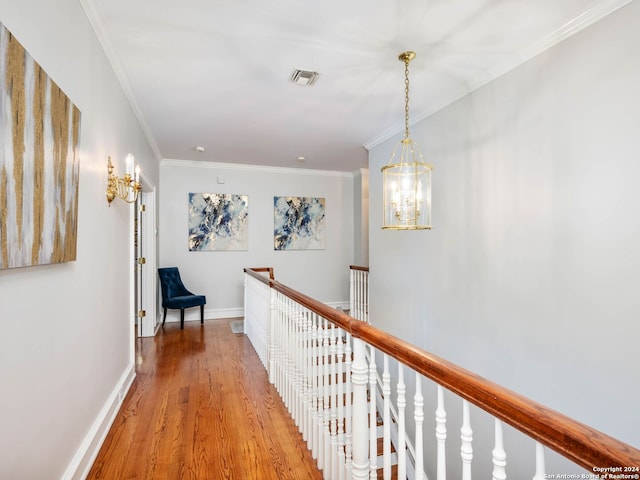 hallway with light hardwood / wood-style flooring, ornamental molding, and a notable chandelier