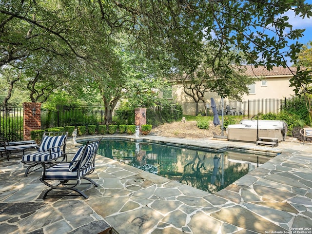 view of pool with a hot tub and a patio area