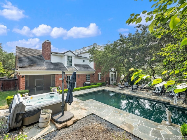 view of swimming pool with a patio area, a sunroom, and a hot tub