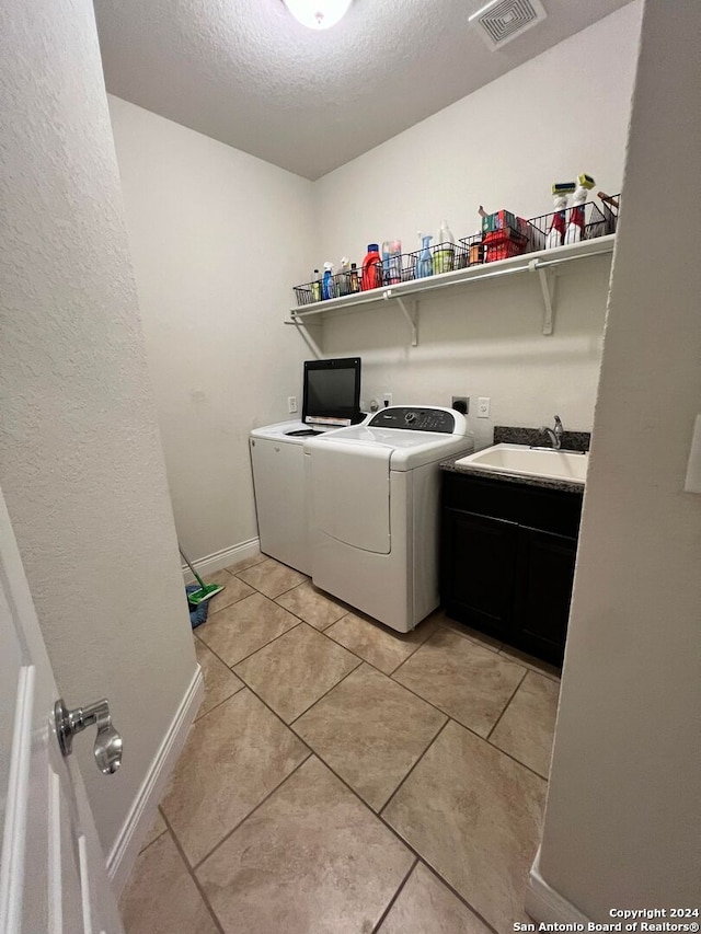 clothes washing area with sink, cabinets, separate washer and dryer, a textured ceiling, and light tile patterned flooring