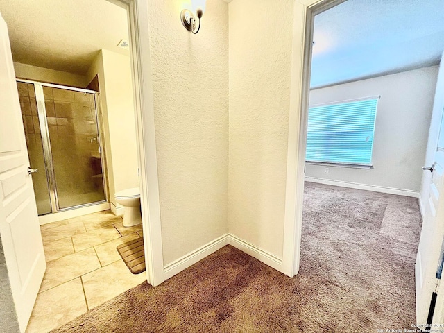 bathroom featuring tile patterned flooring, an enclosed shower, and toilet