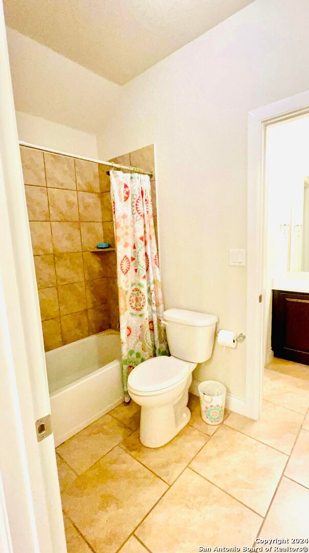 full bathroom with tile patterned flooring, shower / bath combo, vanity, and toilet