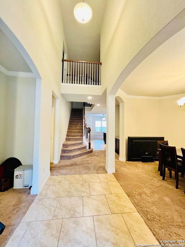 foyer entrance featuring ornamental molding, carpet floors, a high ceiling, and a chandelier