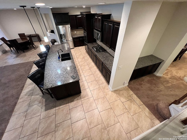 kitchen with light carpet, appliances with stainless steel finishes, light stone counters, a breakfast bar, and sink