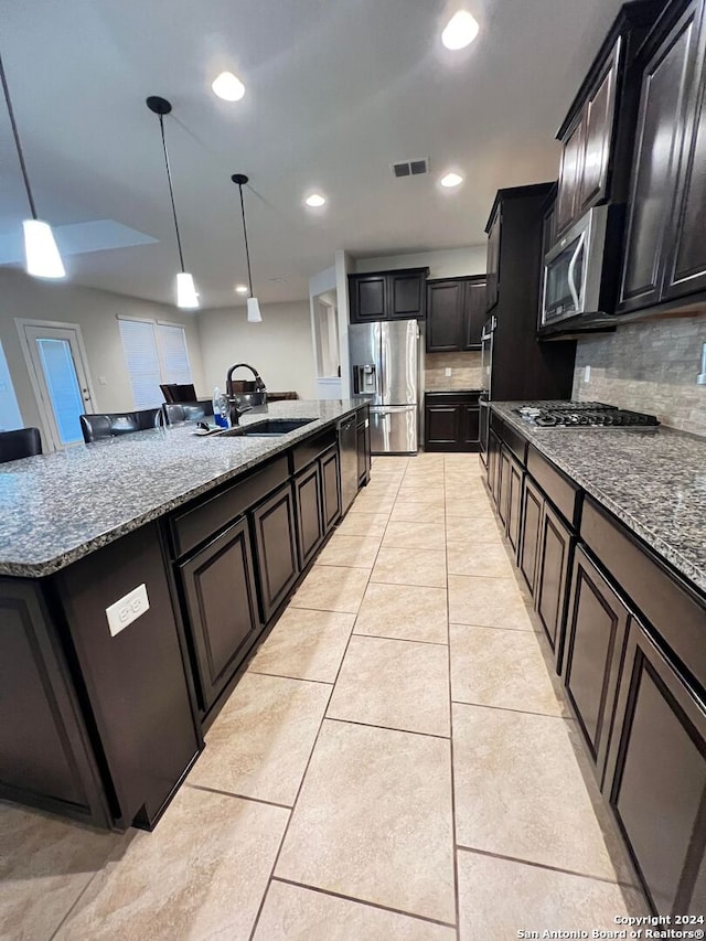 kitchen featuring sink, decorative backsplash, light tile patterned floors, appliances with stainless steel finishes, and decorative light fixtures