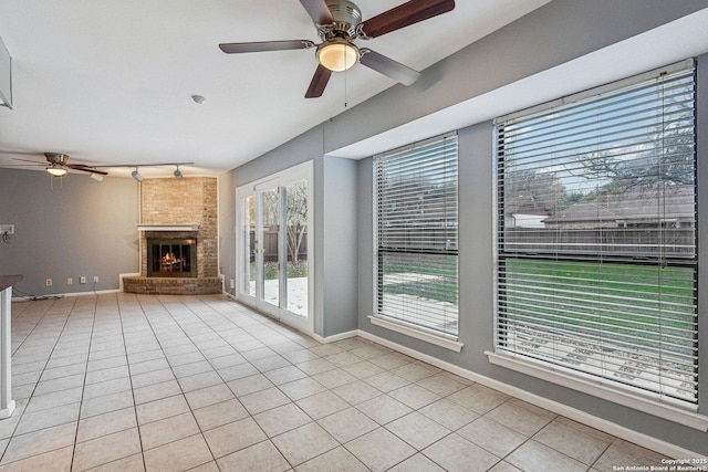 unfurnished living room featuring a fireplace, light tile patterned floors, and ceiling fan