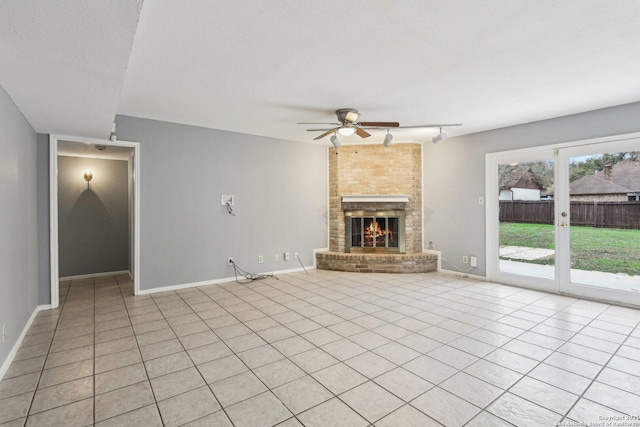 unfurnished living room featuring a large fireplace, ceiling fan, light tile patterned flooring, and a textured ceiling