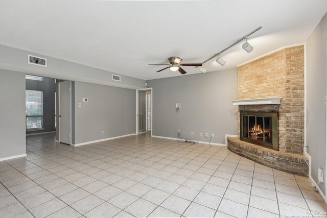 unfurnished living room with ceiling fan, light tile patterned floors, a fireplace, and track lighting