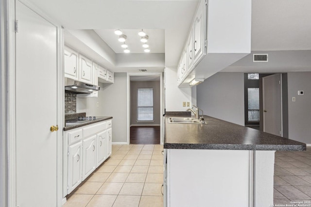 kitchen featuring white cabinets, kitchen peninsula, sink, and light tile patterned floors