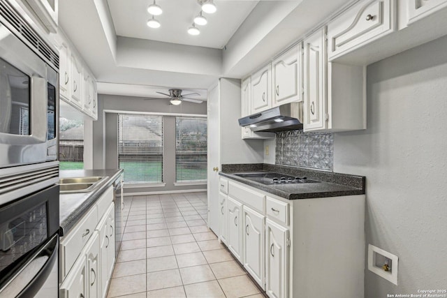 kitchen with black electric stovetop, white cabinets, light tile patterned floors, and tasteful backsplash