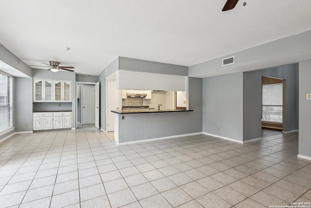 unfurnished living room with light tile patterned floors, ceiling fan, and sink