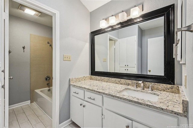 bathroom with tile patterned flooring, vanity, and tiled shower / bath