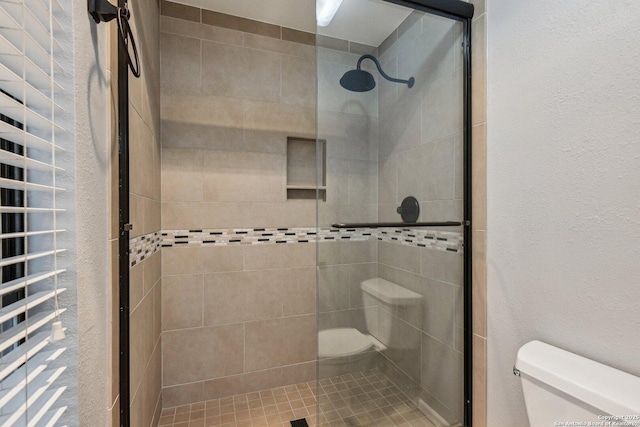 bathroom featuring toilet and a shower with shower door