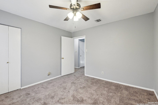 unfurnished bedroom with a closet, light colored carpet, and ceiling fan