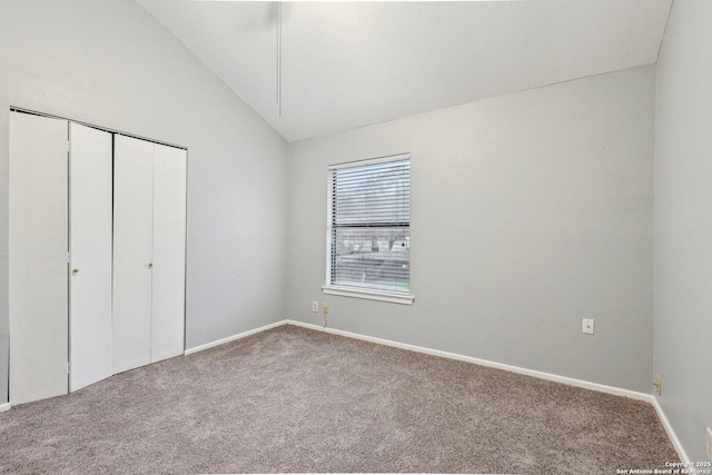 unfurnished bedroom with carpet flooring, a closet, and vaulted ceiling