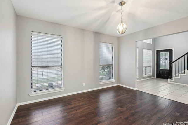 spare room with hardwood / wood-style floors, a healthy amount of sunlight, and a chandelier