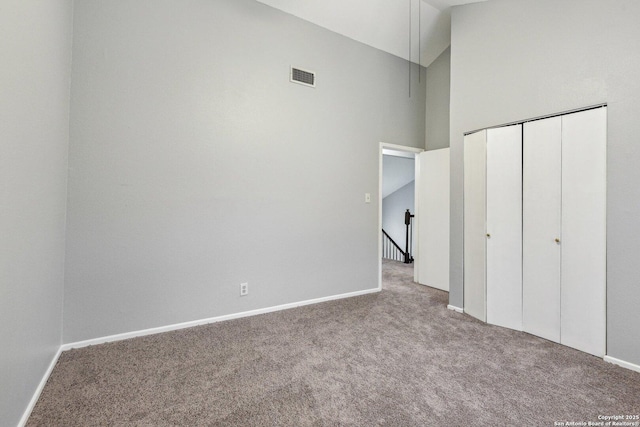 unfurnished bedroom with light carpet, high vaulted ceiling, and a closet