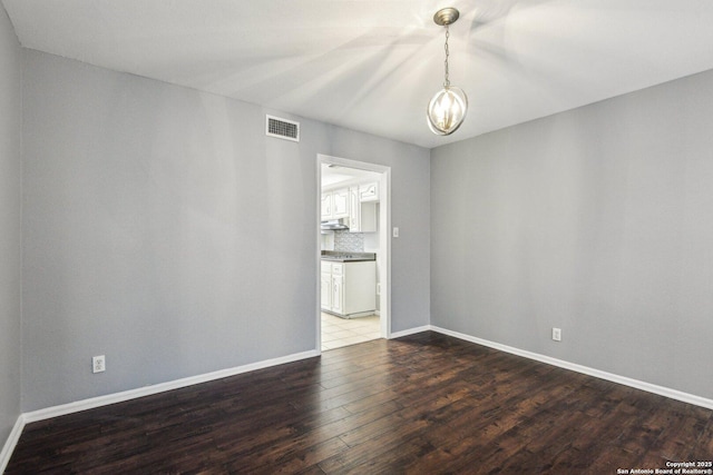 unfurnished room with dark wood-type flooring and a notable chandelier