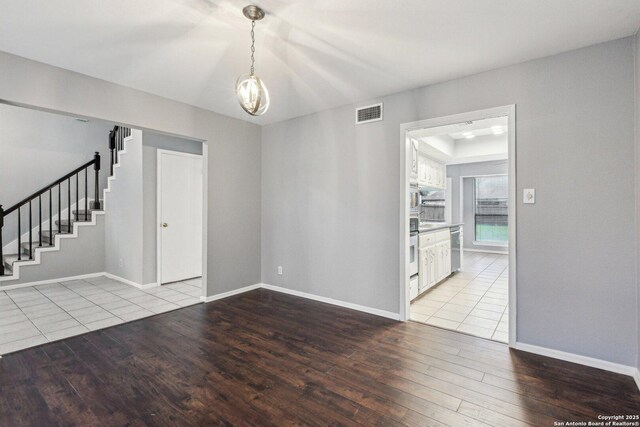 spare room with a barn door, light wood-type flooring, and a chandelier