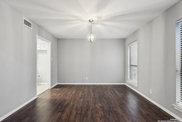 empty room with a chandelier and dark wood-type flooring