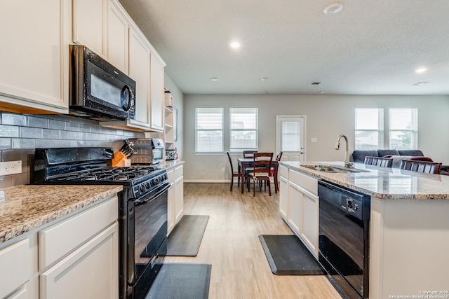 kitchen with white cabinets, sink, backsplash, and black appliances