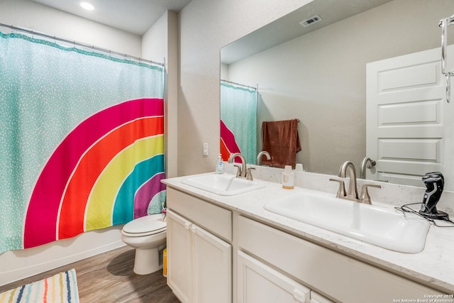 full bathroom with shower / bath combo with shower curtain, hardwood / wood-style floors, vanity, and toilet