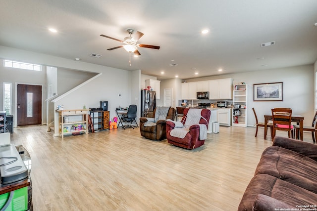 living room with light hardwood / wood-style flooring and ceiling fan