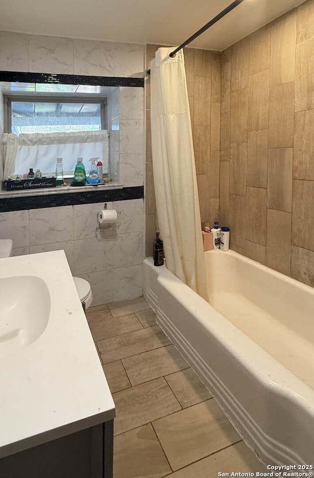 bathroom with shower / bath combination with curtain, vanity, and tile walls