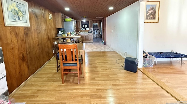 dining area featuring light hardwood / wood-style floors, wooden ceiling, and wooden walls