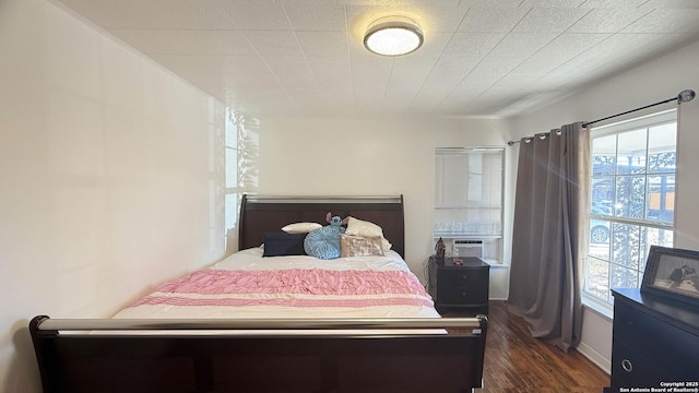 bedroom featuring cooling unit, multiple windows, and dark wood-type flooring