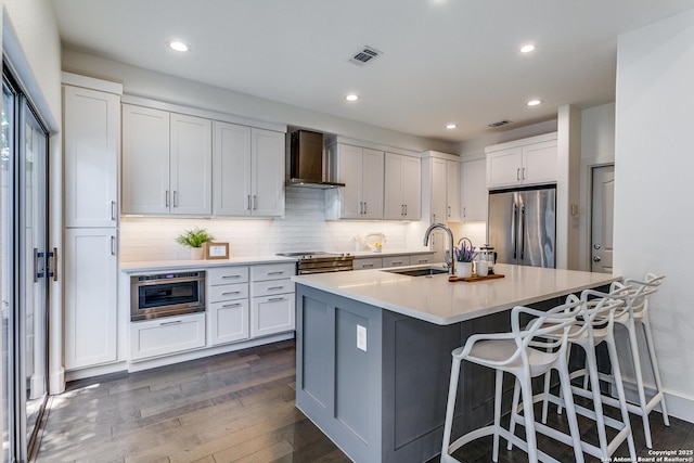 kitchen with white cabinetry, sink, wall chimney exhaust hood, stainless steel appliances, and dark hardwood / wood-style flooring