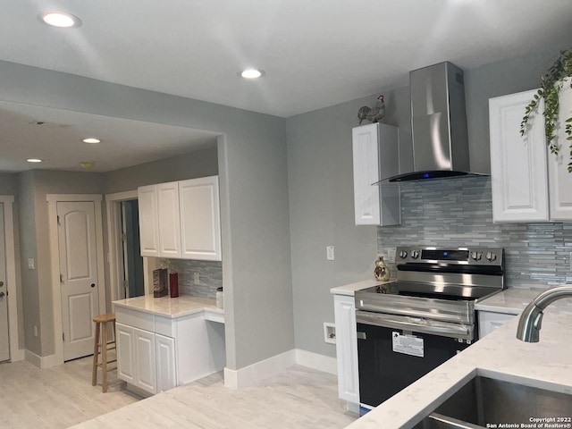 kitchen featuring decorative backsplash, white cabinetry, wall chimney exhaust hood, and stainless steel range with electric cooktop