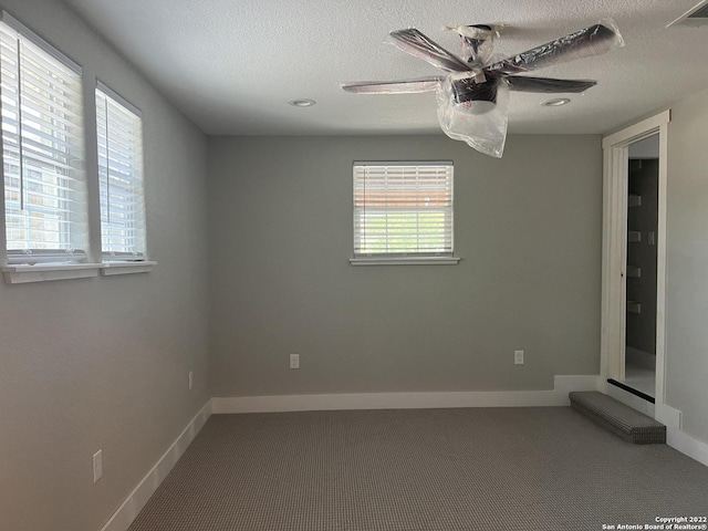 empty room featuring ceiling fan, plenty of natural light, and a textured ceiling