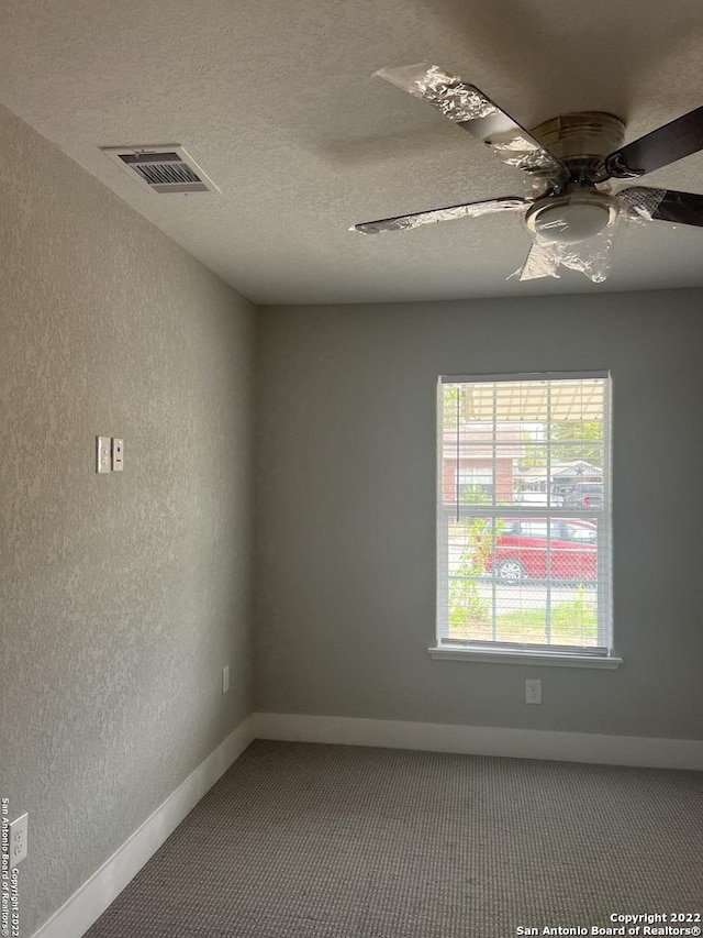 carpeted spare room with ceiling fan and a textured ceiling